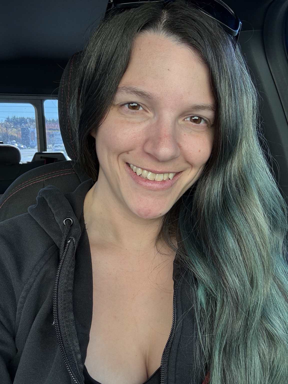 Amanda smiling in a black hoodie with teal in her hair